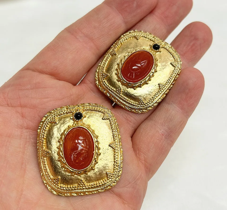 Fabulous statement size 1980s clip on designer style earrings with orange / coral scarab etched center stone.
